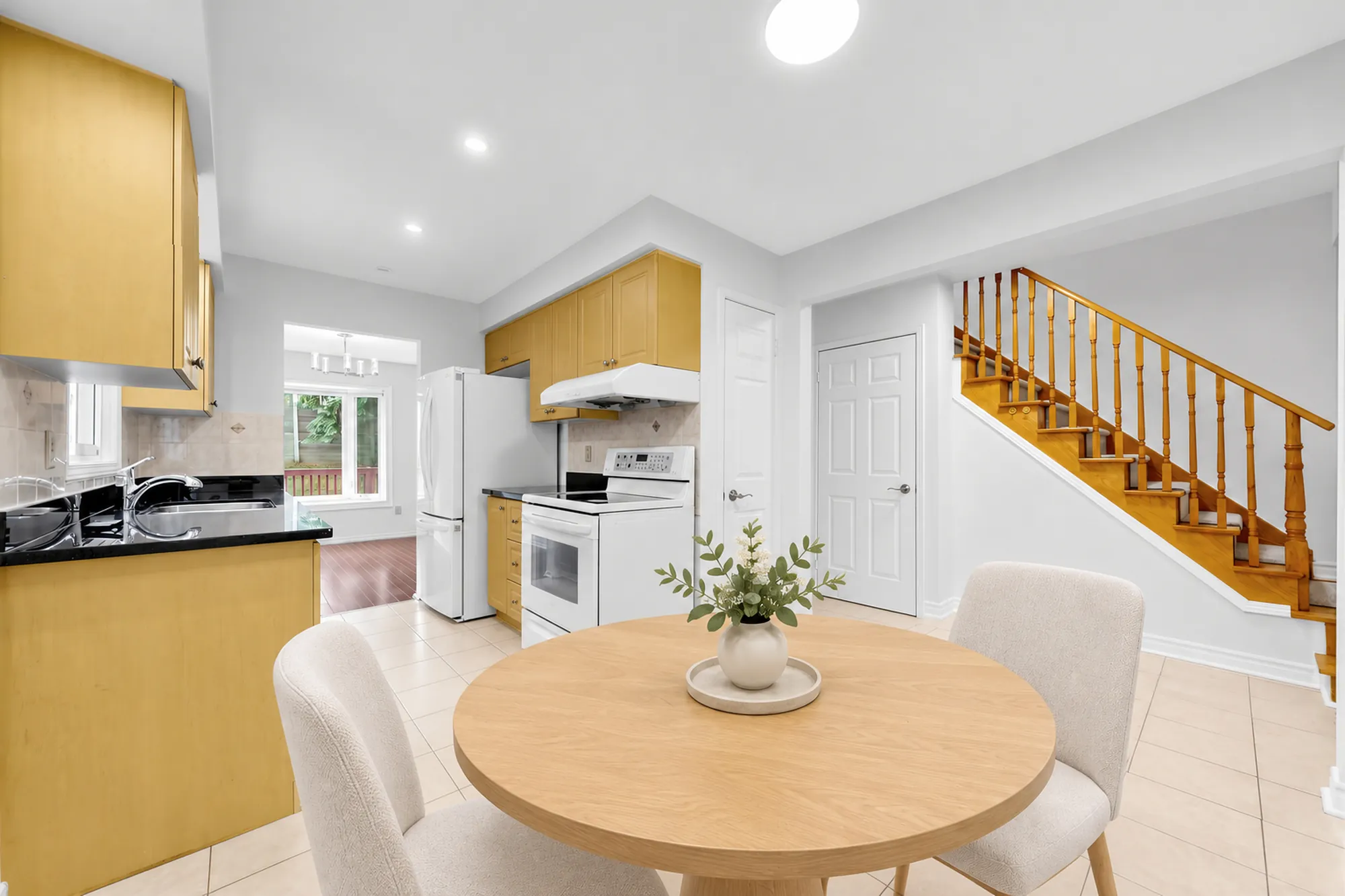 The nook toward the kitchen and the staircase, virtually staged: a round table with a plant in the foreground