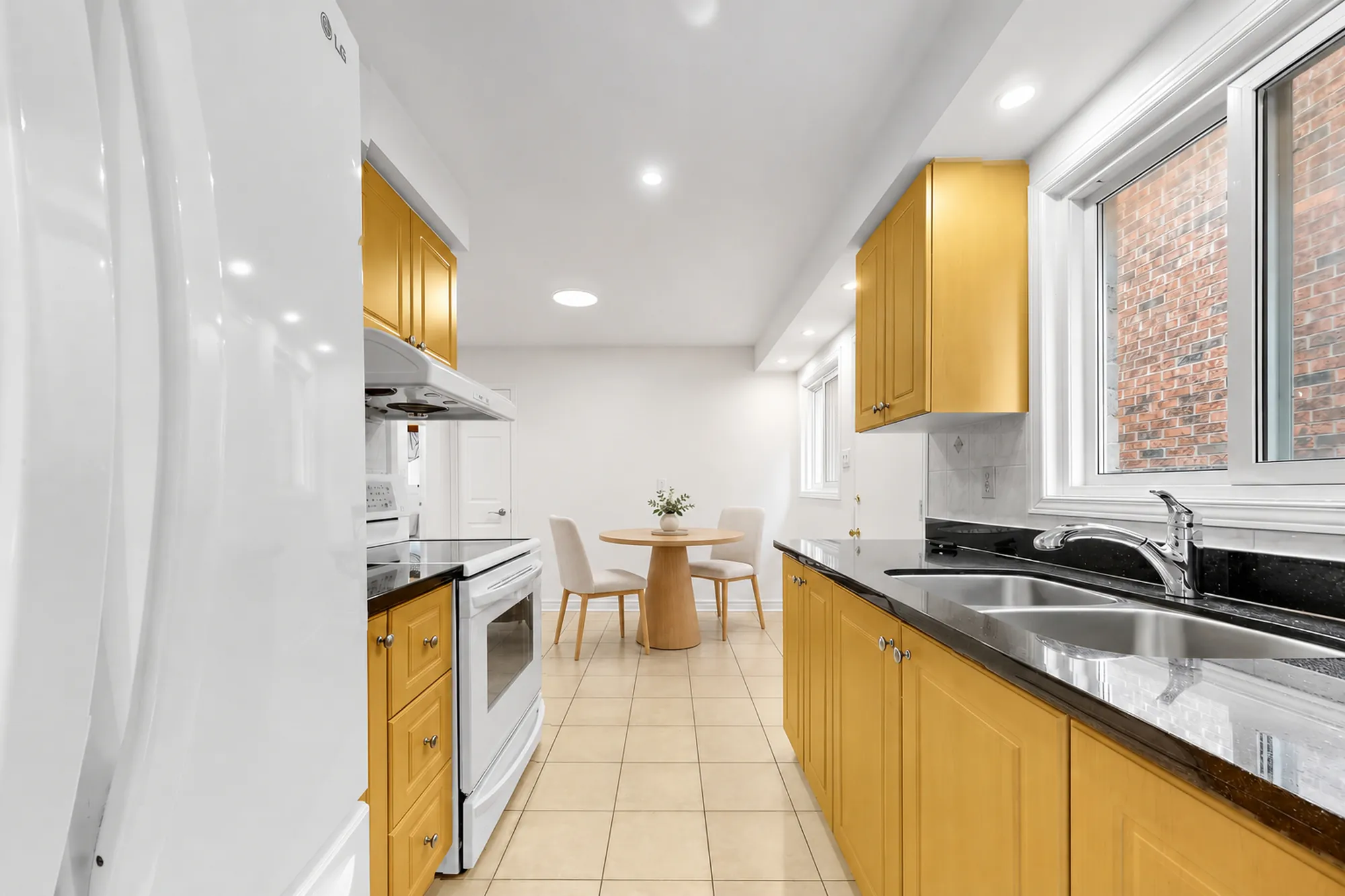 Along the kitchen toward the nook, virtually staged: a round table and chairs by the window at the far end