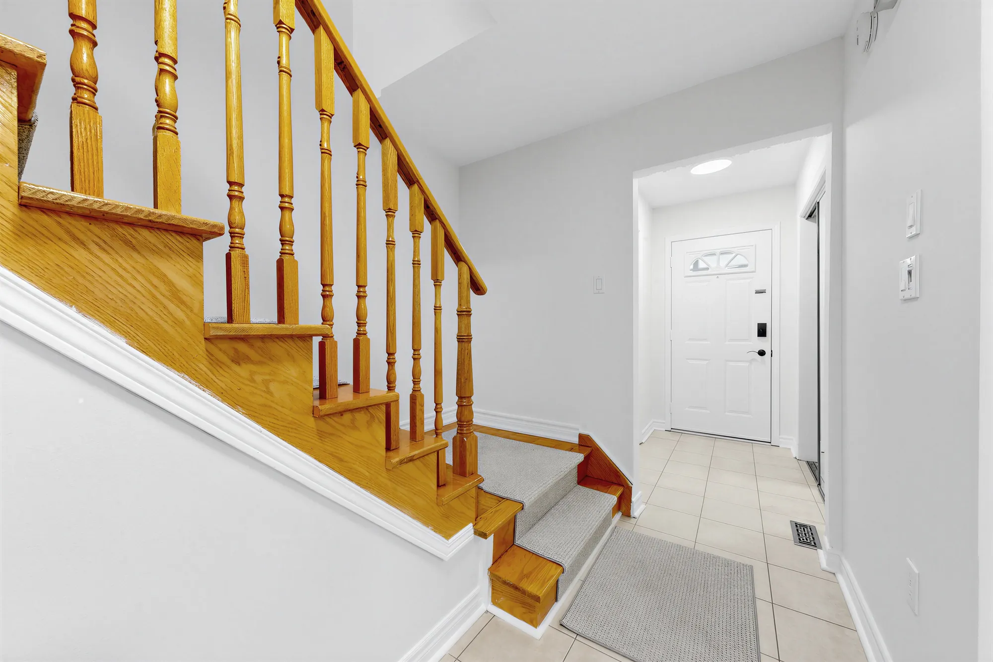 The oak staircase with its runner and turned spindles, the hall to the front door, a tiled floor