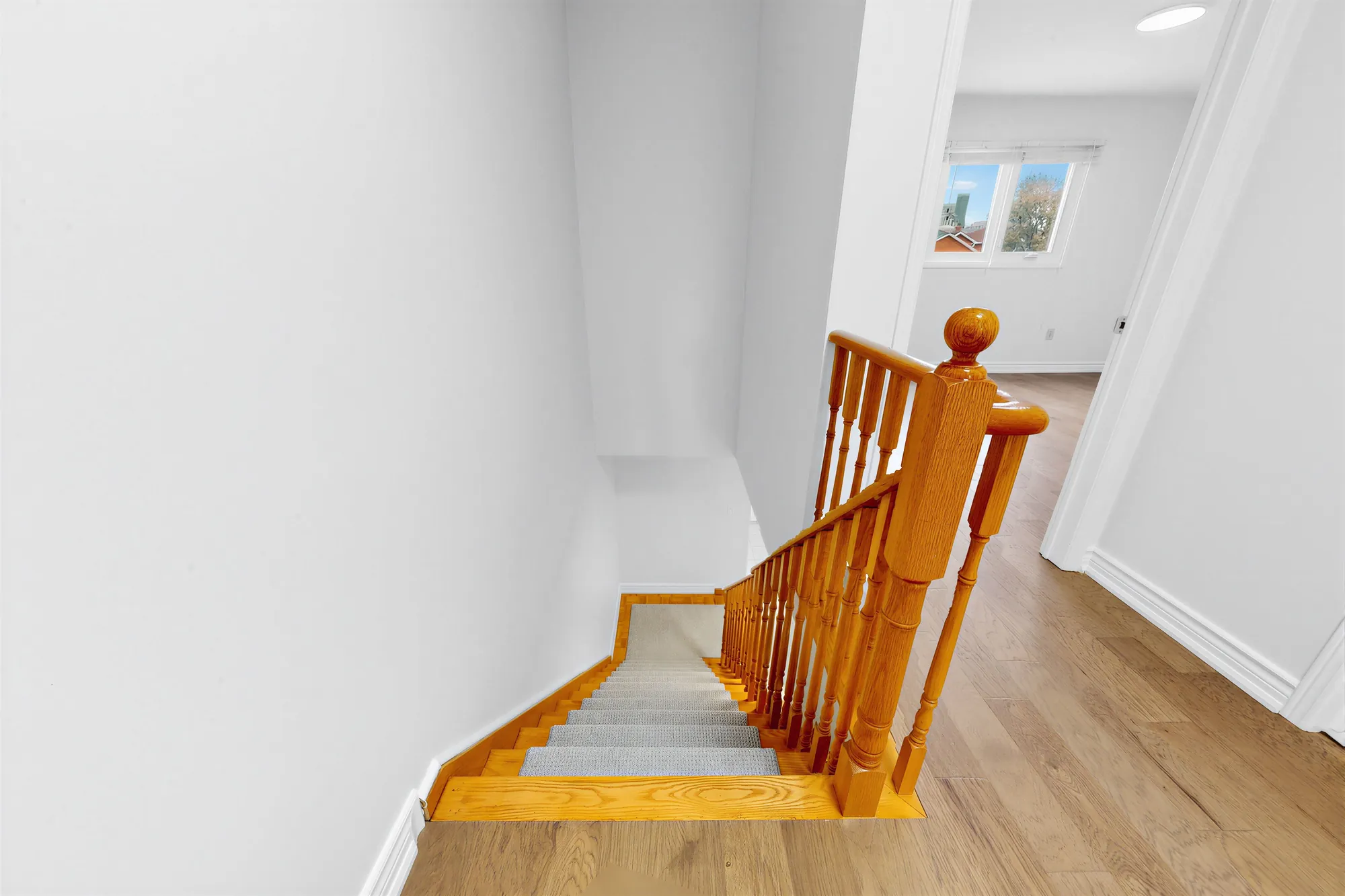 Looking down the oak staircase from the upper hall, a window at the end of the hall